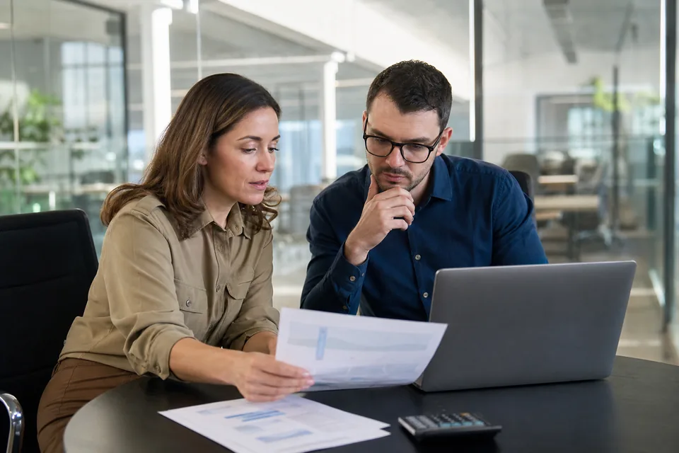 Sales director reviewing CRM seat costs with a finance manager at a meeting table
