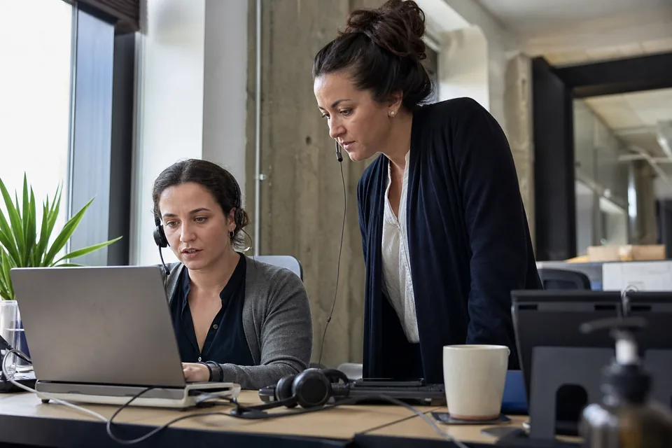 Support team lead checking conversation load with an agent at a desk