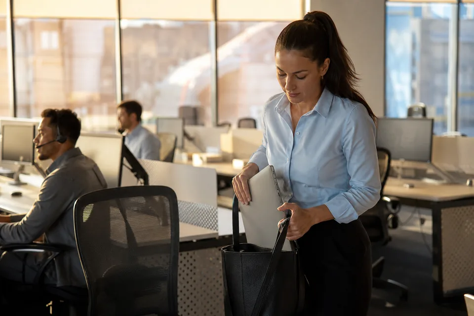 Support agent closing her laptop and leaving her desk at the end of the day